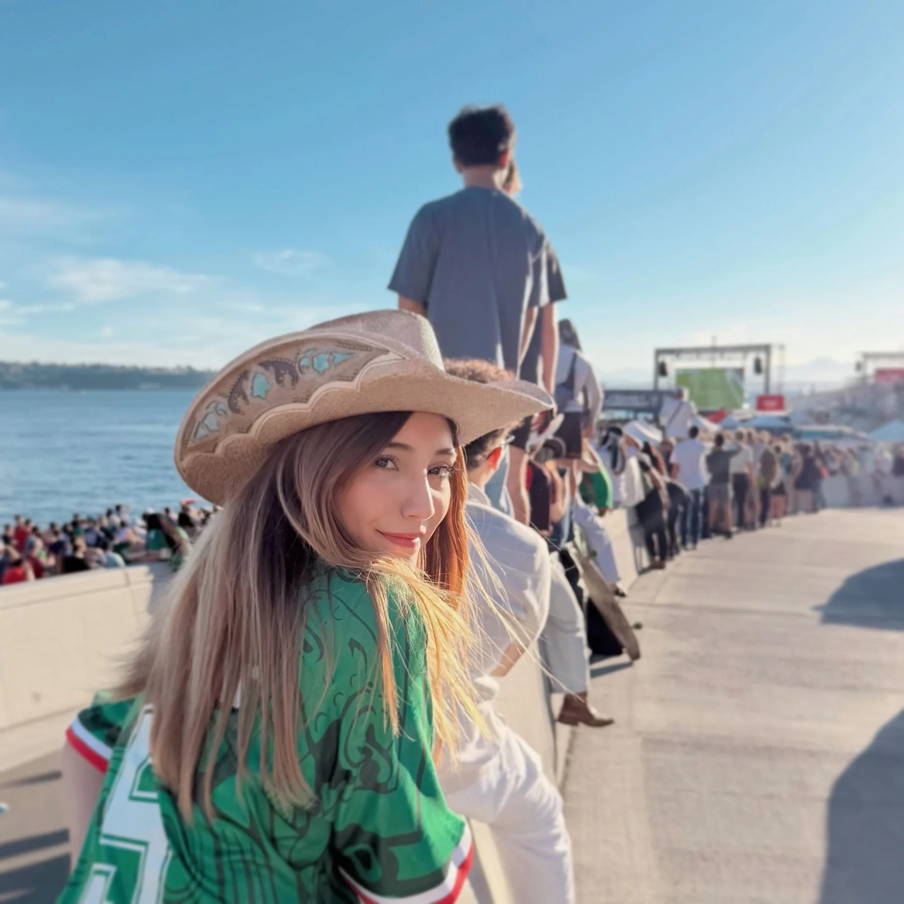Ruby Wu in a cowboy hat by the water, looking back over her shoulder